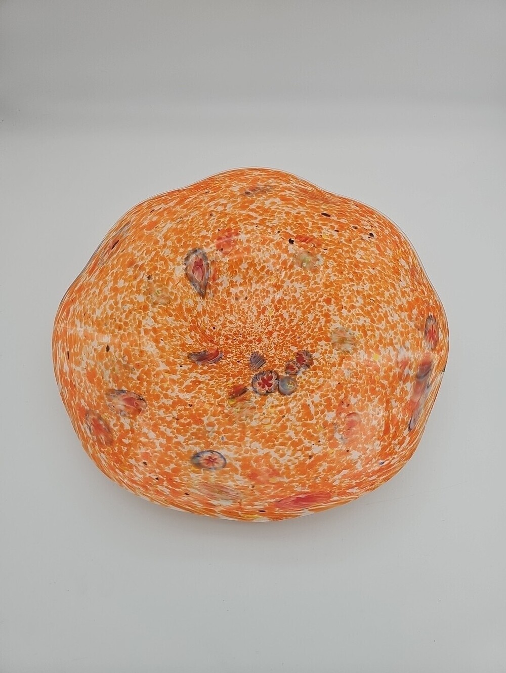 Hand-blown Italian glass bowl with vibrant orange speckles and floral accents.